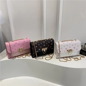 Floral crossbody bag with cherry prints and gold chain in pink, black, and white colors