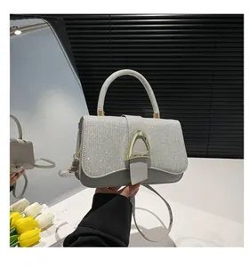 Détail d'un sac à main argenté scintillant avec fermoir doré en D et poignée en cuir