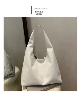 Detail view of white textured faux leather tote bag on grey books and stool