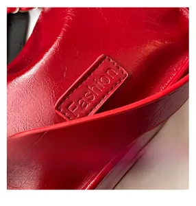 Détail d'un sac en cuir verni rouge brillant avec logo embossé et coutures précises