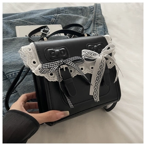 Dettaglio dello zaino in pelle nera con pizzo bianco e fiocchi decorativi femminili
