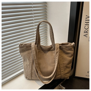 Detail of khaki corduroy tote bag featuring thick texture and front pocket on a windowsill
