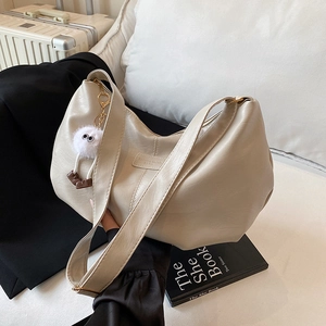 Retro cremeweiße Shopper-Tasche aus Kunstleder mit Plüsch-Anhänger auf stilvollem Sofa