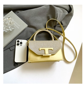 Close-up of golden small square bag with shimmer flap and metallic T-shaped clasp