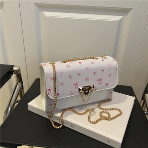 White floral crossbody bag with pink bow pattern and golden chain strap for women