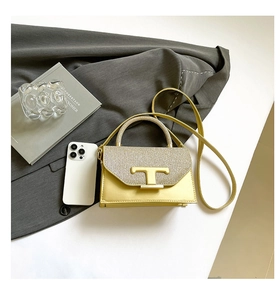 Detail of glitter flap and T-shaped metal clasp on yellow leather shoulder bag