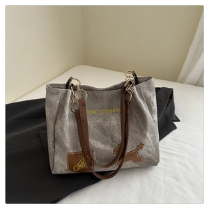 Détail du sac fourre-tout gris en toile avec bandoulière en cuir et écusson chien mignon
