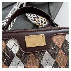 Detail of rhombic pattern fabric with gold plaque and woven shoulder strap on bag