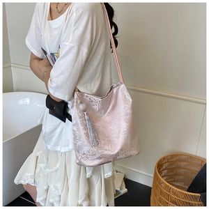 Detail of pink satin bag with silver floral embroidery and hanging tassel ornament