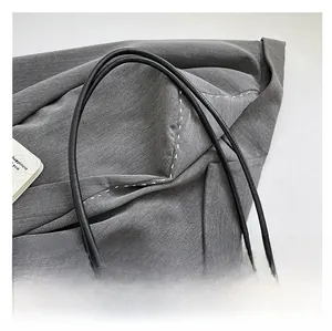 Detail of thin black leather handle with golden metal buckles on straw textured tote bag