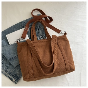 Detailed macro of brown corduroy tote bag showing vertical texture and wide shoulder strap
