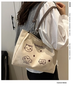 Shoulder view of off-white canvas tote bag featuring cute cat print and leather straps