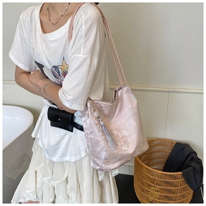 Detail of pink jacquard shoulder bag with silver tassel and sleek silk texture
