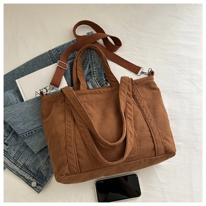 Detailed close-up of brown corduroy tote bag showing ribbed texture and shoulder straps