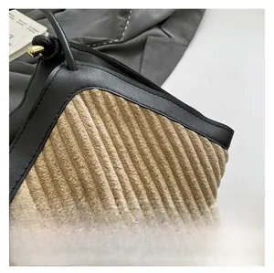 Close-up of beige corduroy tote with black leather trim and golden metal knob detail
