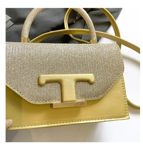 Detailed view of yellow crossbody bag with glitter texture and gold T-shaped metal buckle