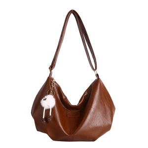 Brown faux leather crescent hobo shoulder bag with a plush charm on white background