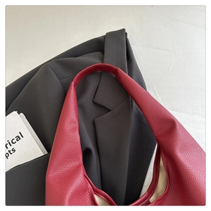 Dettaglio borsa tote in pelle rosso vino con motivo litchi e abito elegante formale