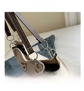 Close-up of canvas tote bag side showing leather straps and silver metal hardware rings