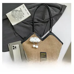 Detailed shot of brown corduroy tote bag with black leather straps and cloud pendant