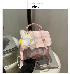 Detail of pink plaid mini backpack with plush pendant and bear print on white stool