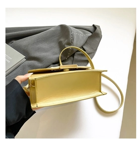 Detail view of a yellow leather crossbody bag showing wide bottom and gold hardware