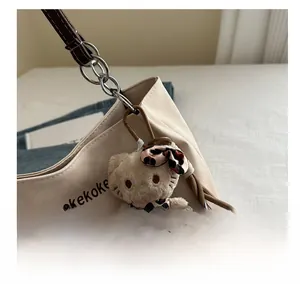 Detail of canvas tote bag featuring plush leopard-print cat charm and chic chain link