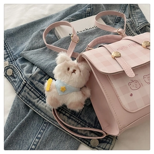 Detail of pink quilted crossbody bag with cute bear illustration and plush bear keychain