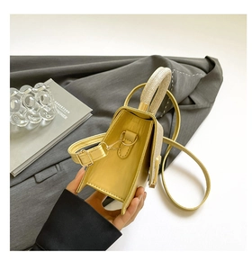 Detail view of yellow leather mini square bag with golden glitter flap and adjustable strap