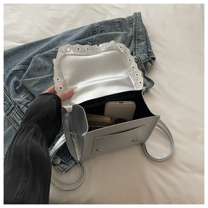 Vista interna dettagliata di una borsa argento con pizzo che mostra la capacità di carico