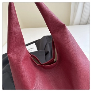 Dettaglio di una borsa tote bordeaux con trama in pelle martellata e apertura a forma di V