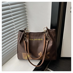 Détail d'un sac cabas marron foncé avec lettres jaunes et patch de silhouette