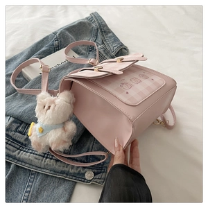 Detail of pink plaid mini backpack featuring three cute bears and a white puppy pendant