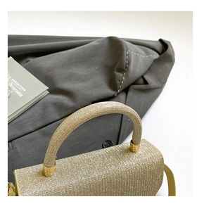 Close-up of golden glitter handbag with a rigid handle for formal evening wear
