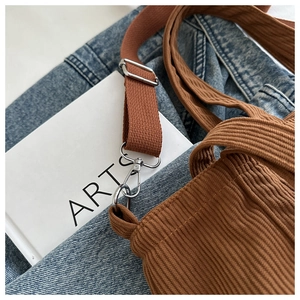 Close-up of brown corduroy shoulder bag showing fabric texture and metal strap hook