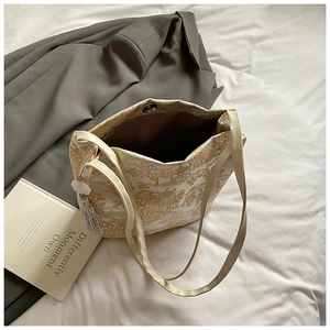 Detailed close-up of jacquard bucket bag with gold mountain patterns and silk tassel charm