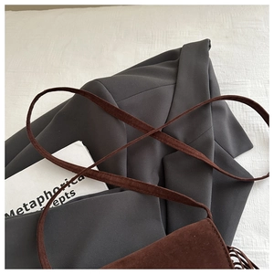 Gros plan sur un sac bandoulière vintage en daim marron avec gland rétro et coutures fines