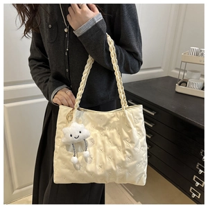 Detail of cream tote bag with bear quilting, braided handles and cloud plush charm