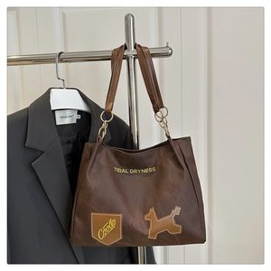 Détail du grand sac cabas marron foncé avec texture mate rétro et écussons graphiques