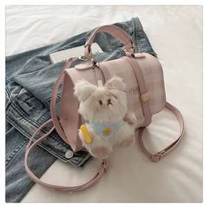Detailed view of pink plaid backpack with a cute white plush bear charm and gold hardware