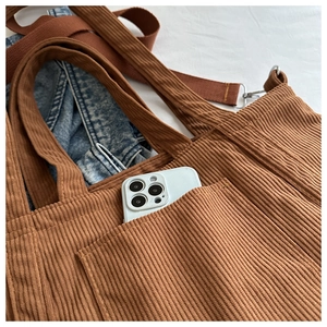Close-up of brown corduroy tote bag showing front pocket with phone storage detail