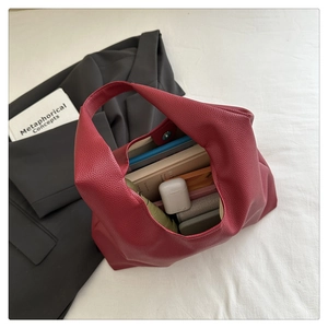 Dettaglio dell'interno spazioso della borsa in pelle bordeaux con oggetti quotidiani