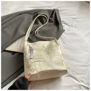 Close-up of traditional floral embroidery and silk texture on a beige bucket bag