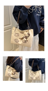Detail of beige canvas tote with leather straps and cute cat plush charm pendant