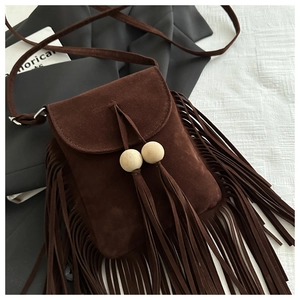 Détail d'un sac bandoulière en daim marron foncé avec longues franges et perles en bois style