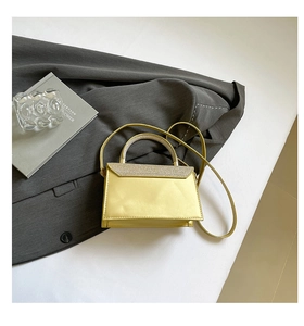 Close-up of a shimmering gold crossbody bag with glitter details on a grey blazer