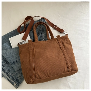 Detailed overhead view of a brown corduroy tote bag with adjustable nylon shoulder strap