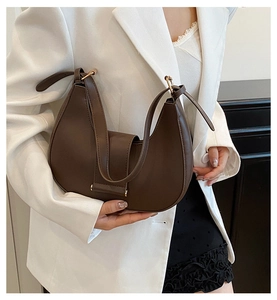 Detail of a minimalist dark brown half-moon underarm bag with a metal buckle strap