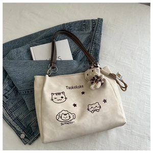 Detail of canvas tote bag featuring cat prints and a plush kitten charm on denim cloth