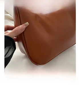 Detail showing soft caramel brown PU leather texture and neat stitching of the crescent bag